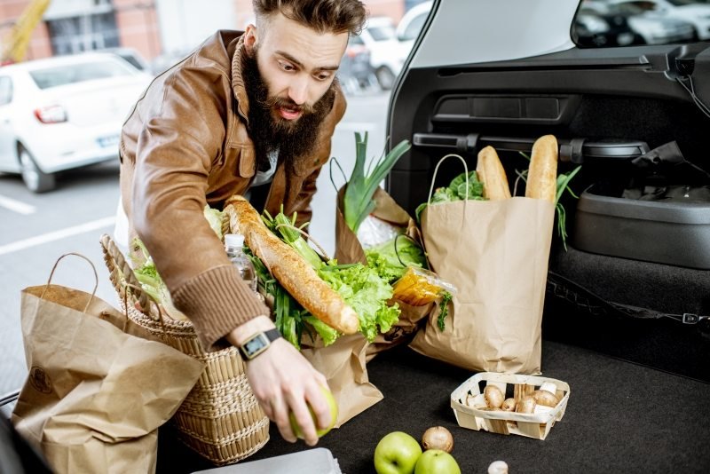 Man keeping goods in reusable grocery bags
